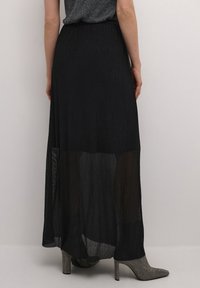 Schwarzer Maxirock aus durchscheinendem, leichtem Material mit fließendem Design. Verfügt über einen geschmockten Bund und transparente Schichten.