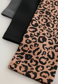 Tri parovi tajica: jedan crne boje, jedan tamno sive i jedan svijetlo smeđi s crnim leopard printom. Svi imaju rebrastu teksturu i elastični materijal.