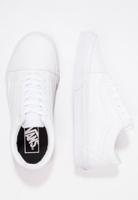 Weiße Leinensneaker mit Gummisohlen, flachen Schnürsenkeln und dezenten Nähten; mit einem schwarzen Logo auf der Innensohle.