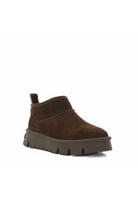 Bottines en cuir suédé marron avec un bout arrondi, une tige basse et une semelle en caoutchouc épaisse, ornée de motifs découpés pour une meilleure adhérence.