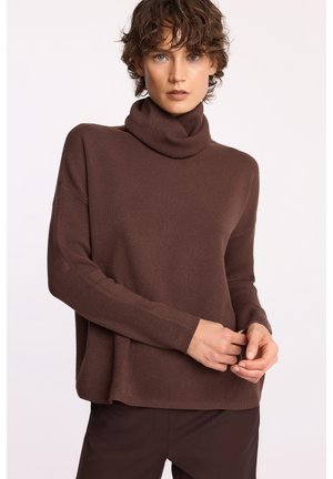 Brązowy sweter typu golf w miękkim dzianinowym materiale, luźny krój z długimi rękawami, z wysokim kołnierzem oraz ściągaczami na mankietach i na dole.