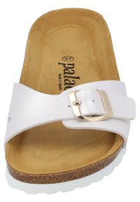 Vit slidåkd sandal med spänne, korkfotbädd och vit gummisula. Har övre i slät läder och en strukturerad insida.