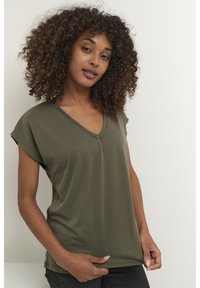 T-shirt vert olive col en V avec manches courtes retroussées, confectionné dans un tissu doux, présentant une coupe décontractée et des détails de design minimalistes.