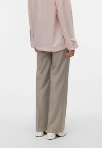 Gestreepte roze en witte langemouwen shirt met knoopmanchetten, gecombineerd met beige wijde broek en blokhak schoenen in het wit tot enkelhoogte.