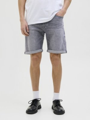 Jeansshorts i en blekgrå tvätt, med uppvikta fållar. I kombination med svarta snörskor och vita ankelsockor. Enkel, avslappnad design.