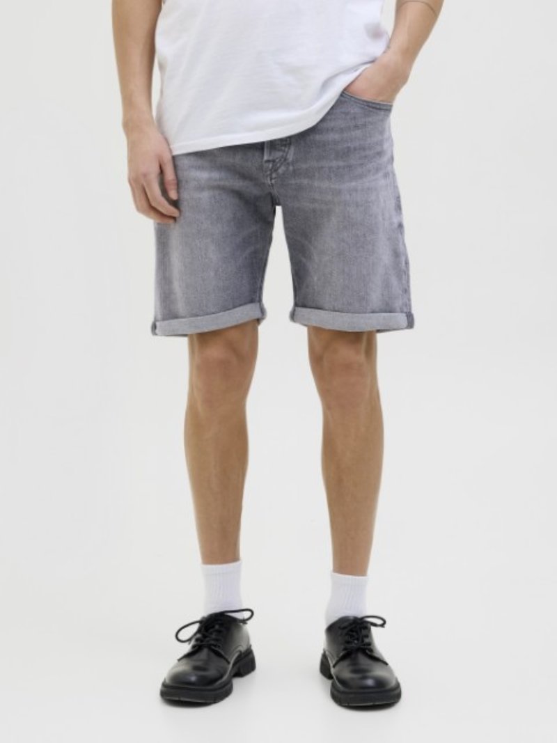 Denimshorts i en falmet gråvask, med opsmøget kant. Kombineret med sorte snørebåndssko og hvide ankelstrømper. Enkel, afslappet design.