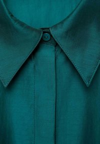 Teal kraagshirt met een gladde textuur, voorzien van een enkele knop bij de kraag en subtiele stiksels langs de naden.