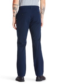 Mörkblå bomullbyxor med rak benstil, utrustade med två bakfickor med knäppning och en platt frontdesign.