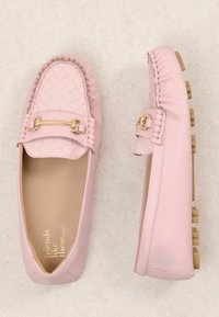 Mocassins roses doux avec embout en texture tissée, détail en métal doré et semelles en caoutchouc à picots, présentés en vues de dessus et de côté sur fond beige.
