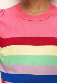 Striktrøje med rund halsudskæring, der har horisontale striber i pink, rød, gul, grøn, lavendel og blå. Blød tekstur og tætsiddende design.