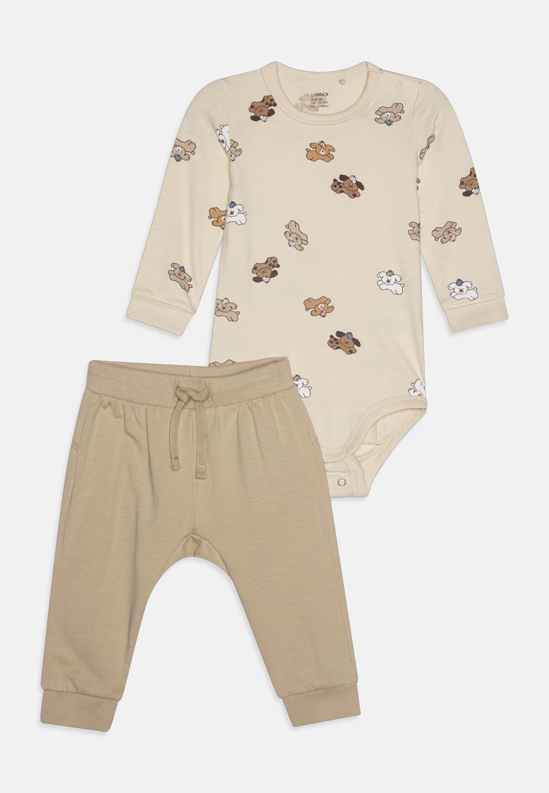 Bežna otroška oblačila, ki vključujejo dolgosleeven bodi z risanimi medvedi in usklajene bež jogger hlače z elastičnim pasom in manšetami.