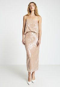 Beiges Paillettenkleid für den Abend mit locker sitzendem Oberteil, figurbetontem Rock und dünnen Trägern. Verfügt über eine glatte Textur und einen dezenten Schimmer.