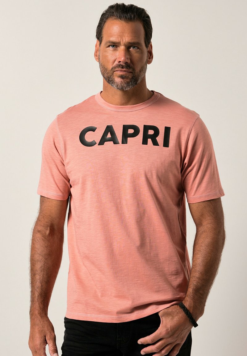 Kortærmet, pink t-shirt lavet af blødt stof med "CAPRI" i fede sorte bogstaver tværs over brystet. Minimalistisk design, rund halsudskæring.