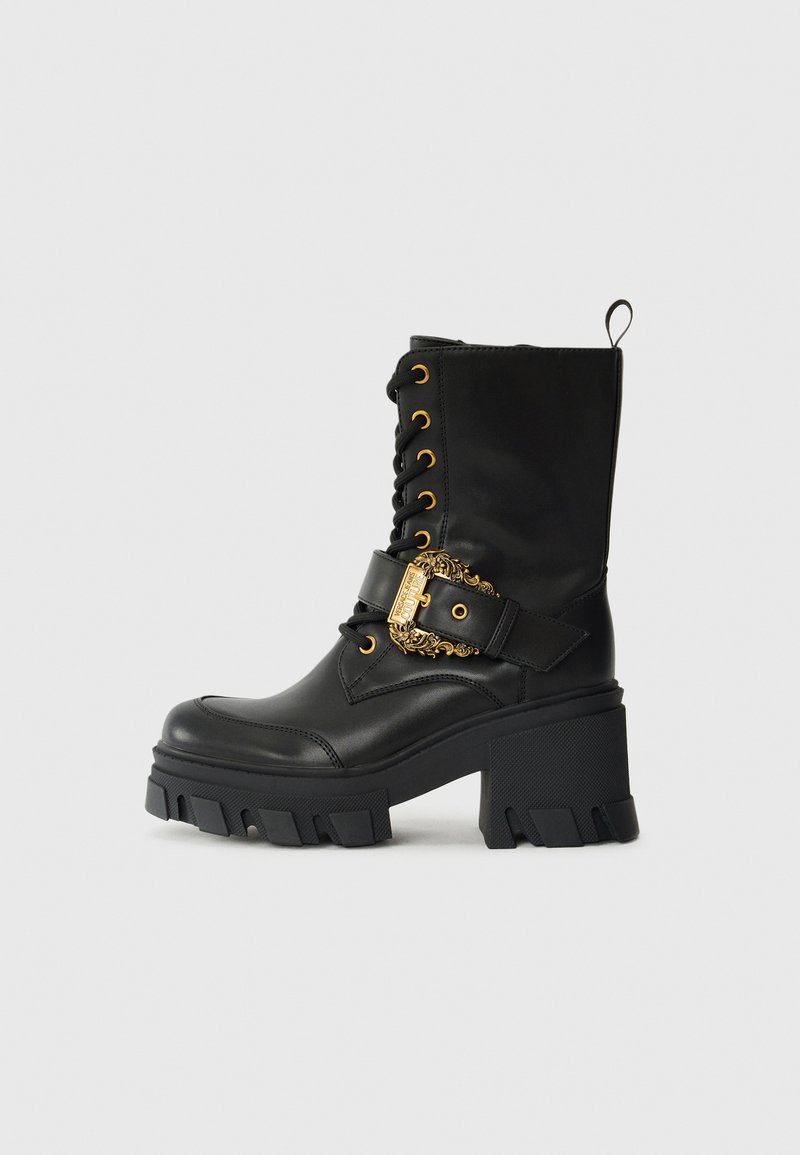 Black ankle boots made of smooth leather with a chunky heel. Features gold hardware, decorative buckle, and lace-up front with gold eyelets.