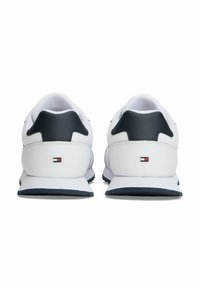 Witte sportschoenen met zwarte accenten, lederen hielondersteuning en een gestructureerd oppervlak met logo detail nabij de zool.