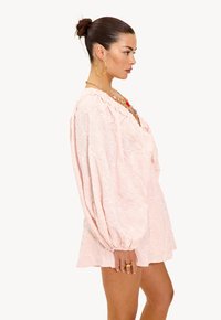 Lichtroze jurk met pofmouwen, bloemendessin en een comfortabele pasvorm. Heeft een V-halslijn en elastische manchetten voor extra comfort.