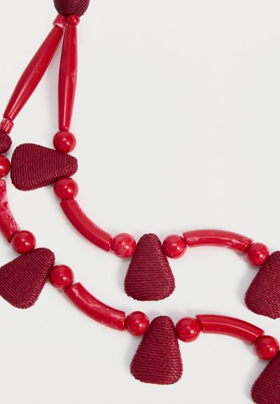 Κόκκινο κολιέ με εναλλασσόμενες λείες στρογγυλές, κυρτές χάντρες και υφασμένες τριγωνικές χάντρες σε φωτεινό φόντο.