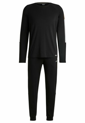 Top a maniche lunghe nere e pantaloni abbinati realizzati in tessuto morbido. Il top presenta strisce a contrasto, dettagli con il logo su entrambi gli articoli e polsini a costine.