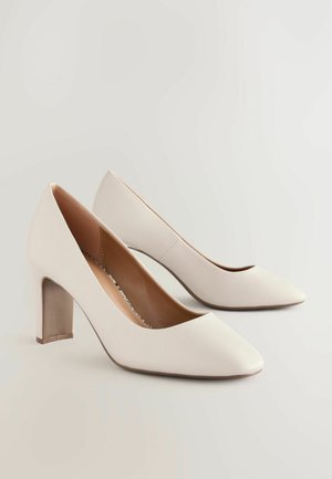 Białe skórzane szpilki z ostro zakończonym noskiem i masywnym obcasem. Teksturowana powierzchnia z gładkim wnętrzem.