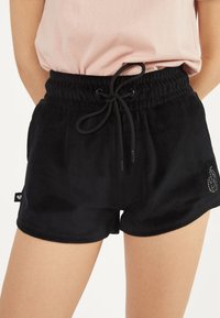 Shorts en velours noir avec une taille élastique, un cordon de serrage réglable, des poches latérales et un accent en strass près de l'ourlet.