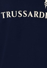 T-shirt in cotone navy con la scritta "TRUSSARDI" stampata in grandi lettere bianche. Tessuto morbido con scollatura a girocollo.