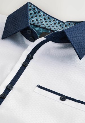 Camicia bianca con colletto a motivi geometrici blu scuro, striscia dei bottoni e bordi della tasca, con bottoni neri e colletto interno a motivo.