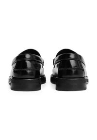 Zwarte lederen instappers met een glanzende afwerking, ronde neus en rubberen zool. Opvallende stiksel en een gladde bovenkant.