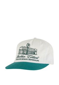 White cap with a teal visor, featuring embroidered "Another Cotton" logo and building illustration. Made of cotton, soft texture.