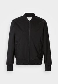 Schwarze Bomberjacke mit Reißverschluss vorne, elastischen Bündchen und Saum, aus leichtem Material. Verfügt über Seitentaschen und ein minimalistisches Branding.