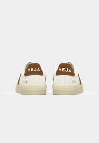 Sneakers bianchi in pelle con dettagli in suede marrone, caratterizzati da una forma arrotondata, suole in gomma e logo "VEJA" sul tallone.