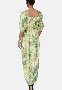 Robe maxi en tissu léger avec un motif floral dans des tones de vert et de jaune, avec des manches bouffantes et un détail de taille froncée.