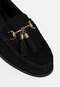 Zwarte suède moccasins met decoratieve gouden hardware en kwastjes. Beschikt over gestikte details langs de randen en een platte rubberen zool.