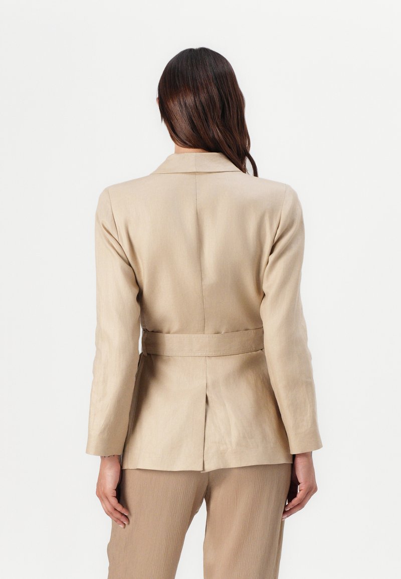 Beige maßgeschneiderter Blazer mit Gürtel, hat einen Reverskragen, eine Rückenbelüftung und lange Ärmel. Hergestellt aus glattem, leichtem Stoff.