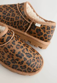 Zapatillas de slip-on con estampado de leopardo y forro de pelo sintético, tonos marrones, suela de goma y detalle de costura en contraste a lo largo de los bordes.