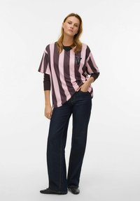 Dryžuota peraugusi rožinės ir tamsiai rudos spalvų marškinėliai su „V“ raidės ženklu kairėje krūtinės pusėje. Derinami su tamsiai platėjančiais džinsais ir juodais batais.