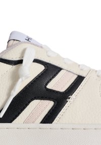 Crème leren sneaker met zwarte en roze accenten, met een gestructureerde afwerking, stevige veters en een opvallend logo ontwerp.
