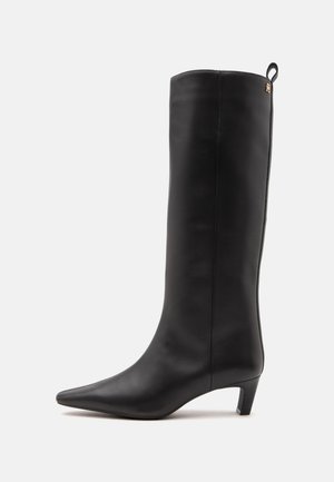 Botte en cuir noire montante jusqu'au genou avec bout pointu, talon bas et languette d'aide au pied à l'arrière en haut.