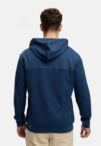 Marineblauwe hoodie met een gestructureerd lijf en gladde bovenstukken. Beschikt over lange mouwen en een geribbelde zoom voor een goede pasvorm.