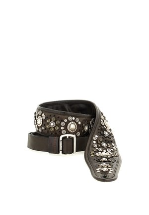 Cintura in pelle nera decorata con borchie metalliche argentate e nere che formano motivi floreali e circolari, arrotolata e parzialmente svolta.