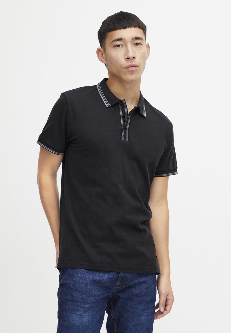 Svart polo skjorte med krage som har grå stripete detaljer, korte ermer og knappestolpe; glatt bomullsstoff, tettsittende design.