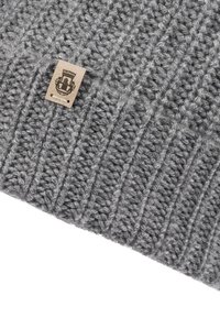 Gray knitted fabric with ribbed pattern and a small beige tag featuring a black emblem stitched near the edge.