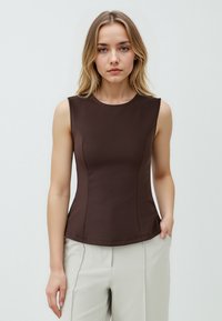 Top marrone senza maniche con scollatura rotonda, corpino aderente e dettagli di cucitura sottili, abbinato a pantaloni chiari.