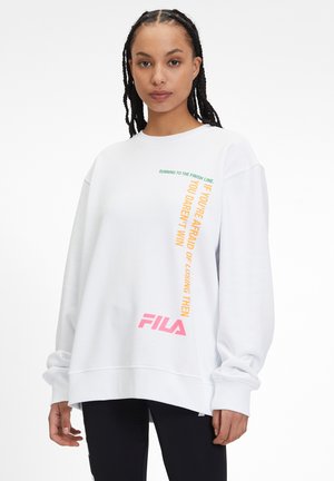 Felpa bianca con testo verde e arancione, "CORRENDO VERSO IL TRAGUARDO" e "SE HAI PAURA DI PERDERE ALLORA," con logo Fila rosa.