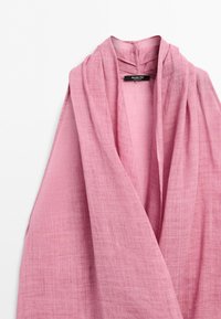 Roze lichtgewicht linnen sjaal met een zachte textuur, losjes gedrapeerd met een zichtbaar zwart merkembleem in het kraaggebied.