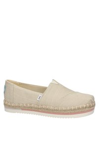 Chaussure beige en toile à enfiler avec une semelle intermédiaire en jute tressé, une semelle extérieure en caoutchouc blanc et une petite étiquette de marque en tissu sur le côté et le talon.