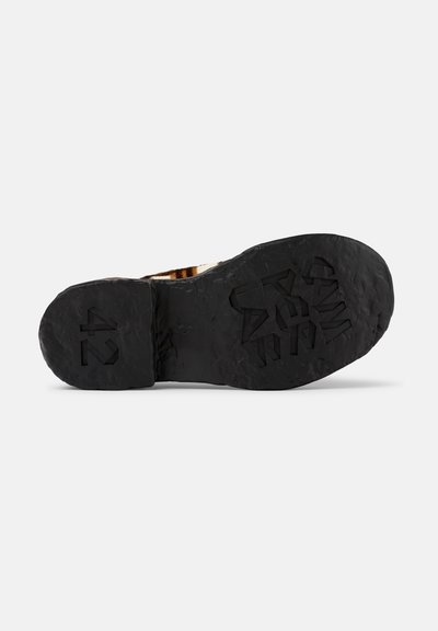 Zwarte rubberen zool van een schoen met een textuurpatroon voor grip en een geprofileerde maat "42" detail, met een robuuste, ongelijkmatige oppervlakte.