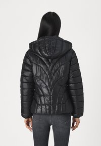 Giacca a vento nera con cappuccio, caratterizzata da un motivo trapuntato diagonale e una texture lucida. I polsini a coste e un design aderente aumentano il calore.