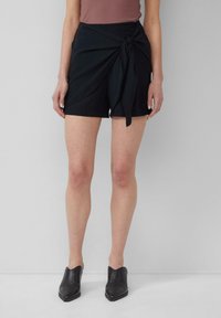 Zwarte shorts met een geknoopte taille detail, gemaakt van lichtgewicht stof. Het ontwerp heeft een ontspannen pasvorm en een soepele textuur.