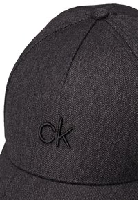Căciulă de baseball neagră dintr-un material texturat, cu un logo brodat "ck" pe față. Vizor curb și design cu coroană structurată.