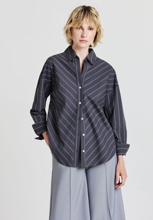 Camicia a righe grigia scura con collo a camicia, bottoni sul davanti e maniche lunghe, caratterizzata da righe bianche diagonali e una vestibilità rilassata.
